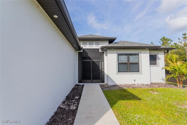 view of exterior entry featuring a lawn