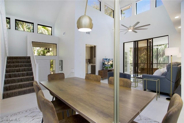 dining room featuring tile patterned floors, ceiling fan, and a towering ceiling