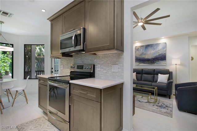 kitchen with backsplash, ceiling fan, pendant lighting, and stainless steel appliances