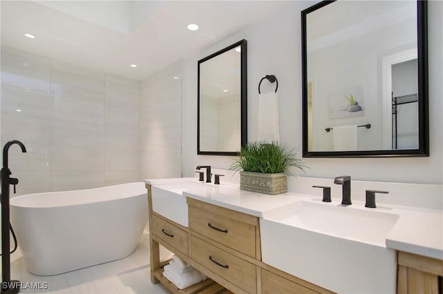 bathroom featuring tile patterned flooring, a bath, and vanity