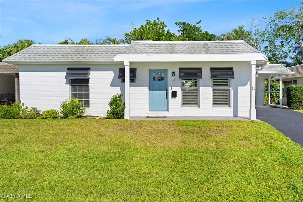 11 Knights Bridge Rd, Naples, FL 34112 - single story home with a front lawn, driveway, an attached carport, and a shingled roof