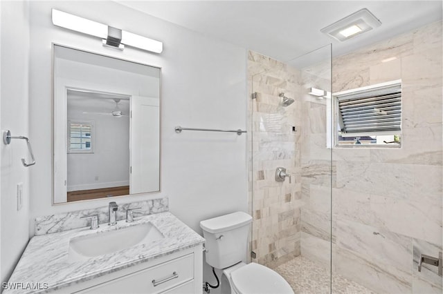 bathroom featuring toilet, a tile shower, and vanity