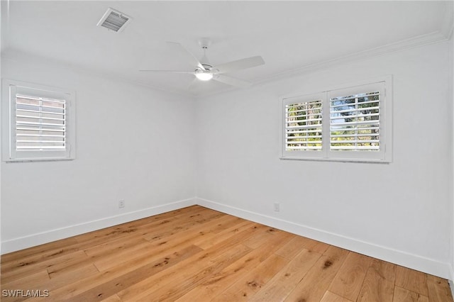 spare room featuring baseboards, visible vents, ceiling fan, crown molding, and light wood-type flooring