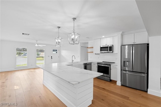 kitchen with a peninsula, appliances with stainless steel finishes, a sink, and light wood-style floors