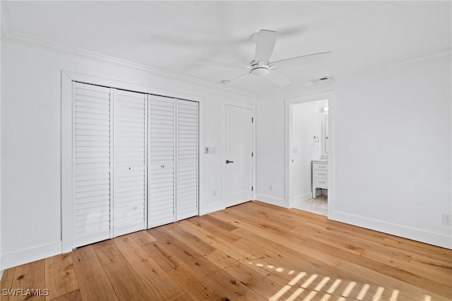 unfurnished bedroom with connected bathroom, hardwood / wood-style flooring, baseboards, a closet, and crown molding