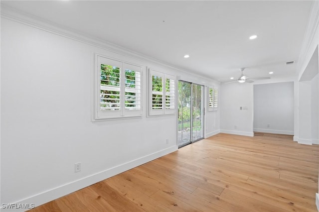 spare room featuring light wood-type flooring, crown molding, and baseboards