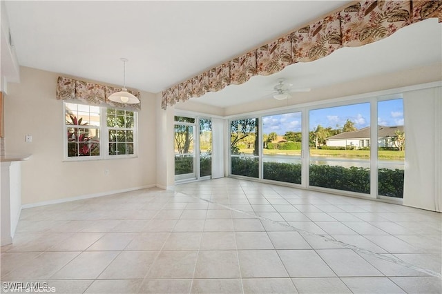 interior space featuring a water view, light tile patterned floors, ceiling fan, and a healthy amount of sunlight