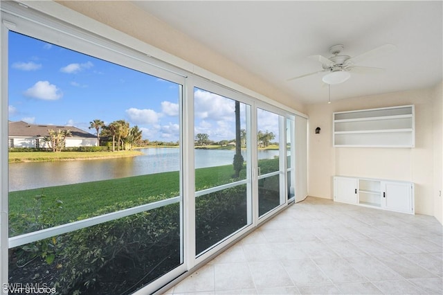 unfurnished sunroom featuring ceiling fan and a water view