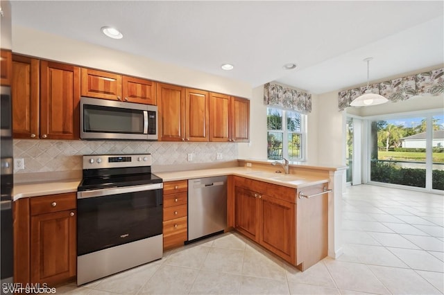 kitchen featuring appliances with stainless steel finishes, sink, hanging light fixtures, kitchen peninsula, and light tile patterned flooring