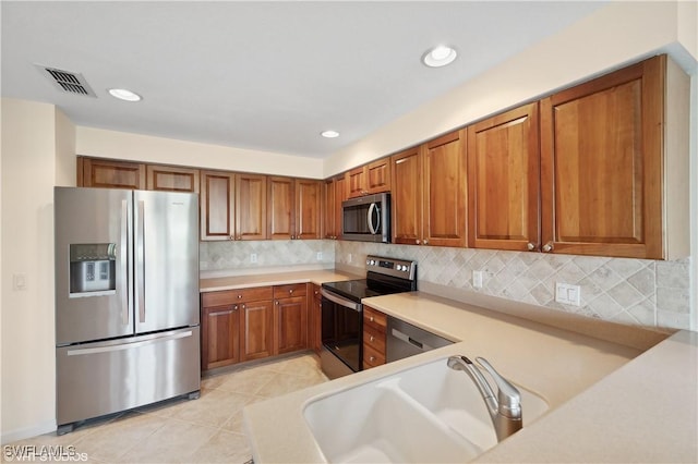 kitchen featuring decorative backsplash, appliances with stainless steel finishes, sink, and light tile patterned flooring