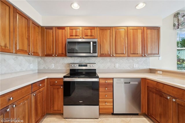 kitchen featuring light tile patterned floors, stainless steel appliances, backsplash, and sink