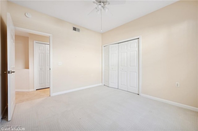 unfurnished bedroom featuring ceiling fan, light colored carpet, and a closet