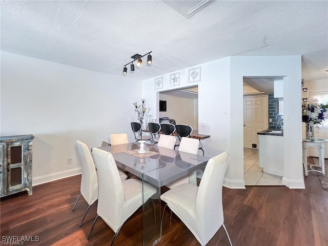 dining area with hardwood / wood-style floors, a textured ceiling, and rail lighting