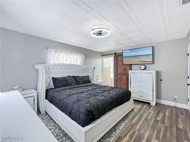 bedroom featuring dark hardwood / wood-style flooring and a barn door