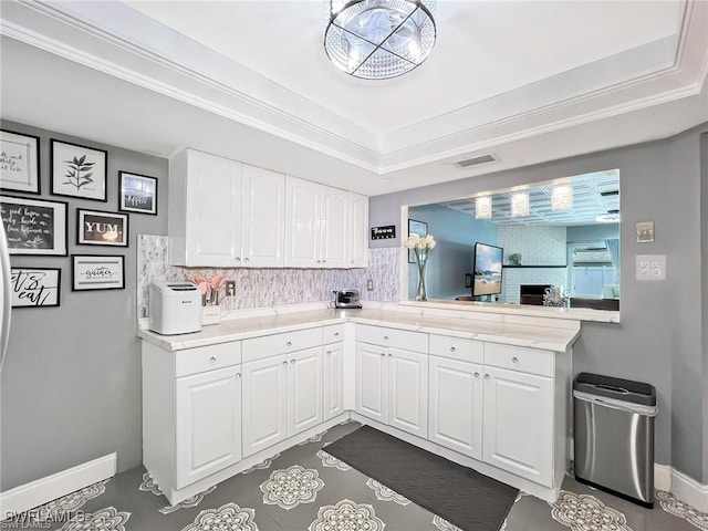 kitchen with a tray ceiling, decorative backsplash, white cabinetry, and ornamental molding