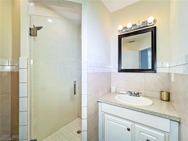 bathroom with vanity, a shower with shower door, and tile walls