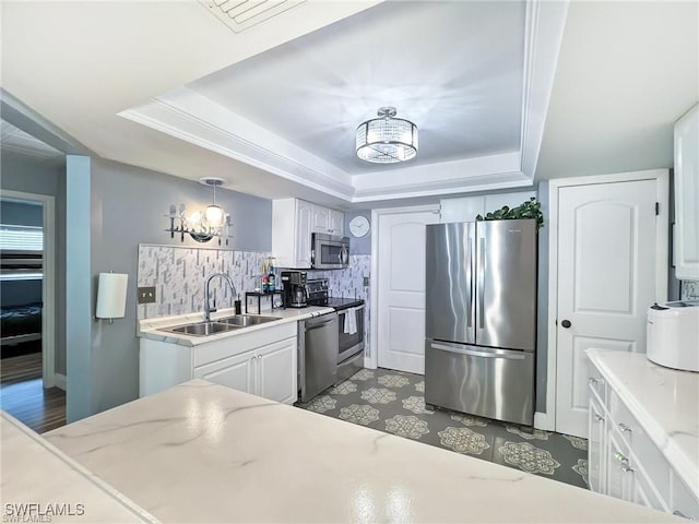 kitchen featuring a raised ceiling, white cabinetry, pendant lighting, and appliances with stainless steel finishes