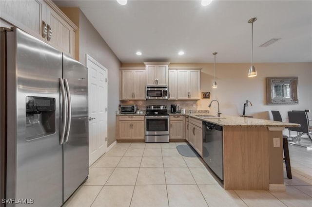 kitchen with a kitchen breakfast bar, kitchen peninsula, decorative light fixtures, light brown cabinetry, and appliances with stainless steel finishes