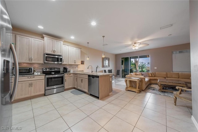 kitchen with kitchen peninsula, appliances with stainless steel finishes, light brown cabinetry, ceiling fan, and decorative light fixtures