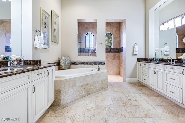 bathroom with vanity and tiled tub