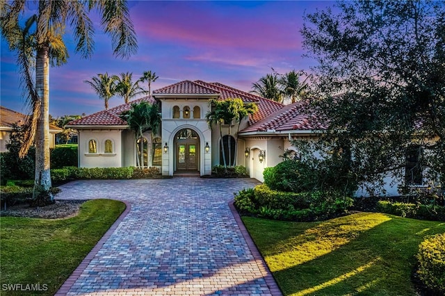 mediterranean / spanish home featuring a yard and french doors