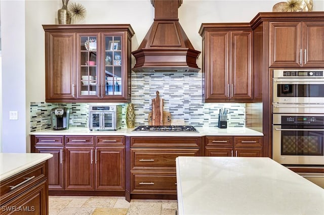 kitchen featuring stainless steel appliances, custom range hood, and decorative backsplash