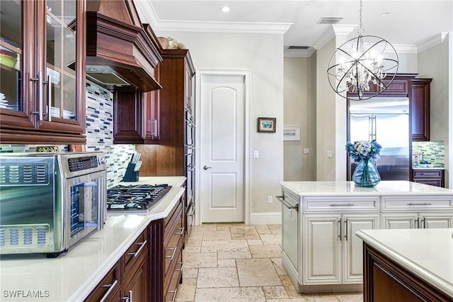 kitchen with backsplash, appliances with stainless steel finishes, custom range hood, and an inviting chandelier