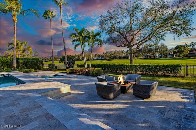 patio terrace at dusk with a fire pit and a fenced in pool