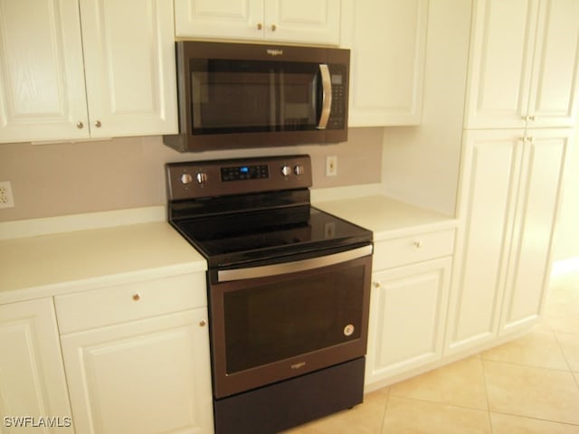 kitchen with white cabinetry, light tile patterned floors, and stainless steel electric range