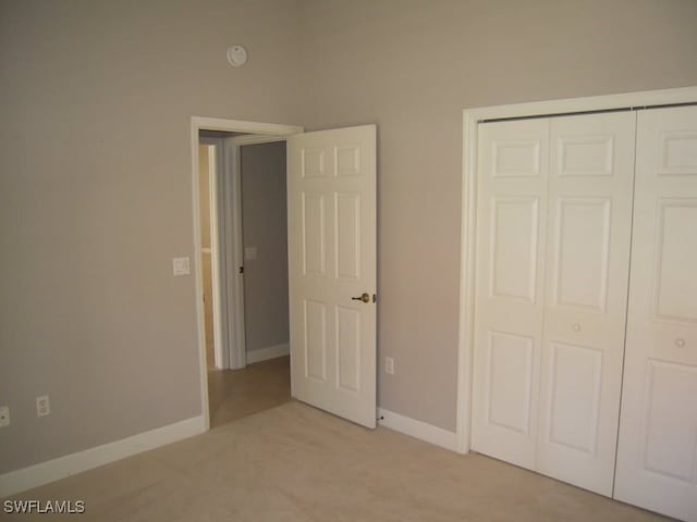 unfurnished bedroom with light carpet and a closet