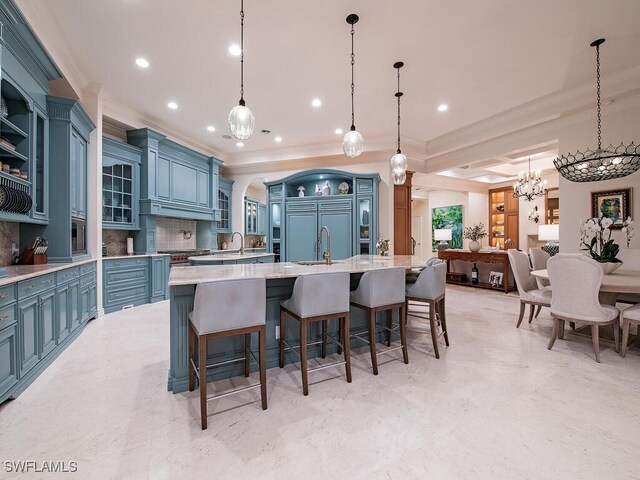 kitchen with pendant lighting, tasteful backsplash, a breakfast bar area, a large island with sink, and crown molding