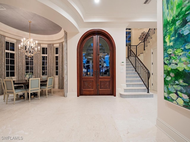 foyer entrance with stairs, a raised ceiling, french doors, and ornamental molding