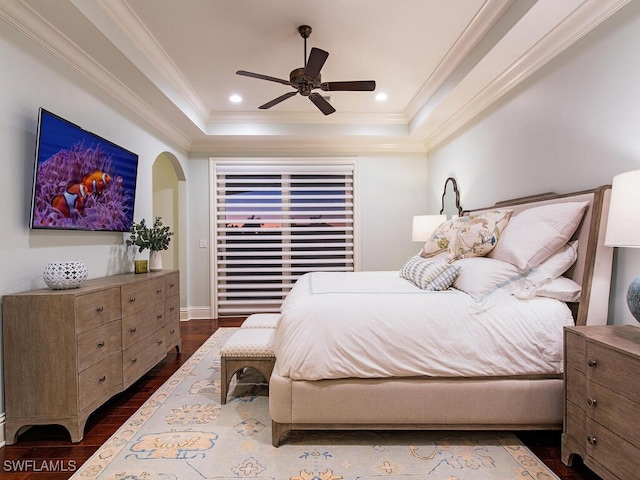 bedroom featuring a tray ceiling, recessed lighting, arched walkways, ornamental molding, and dark wood-type flooring