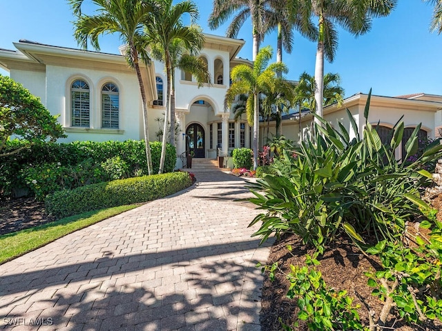 property entrance with decorative driveway, french doors, and stucco siding