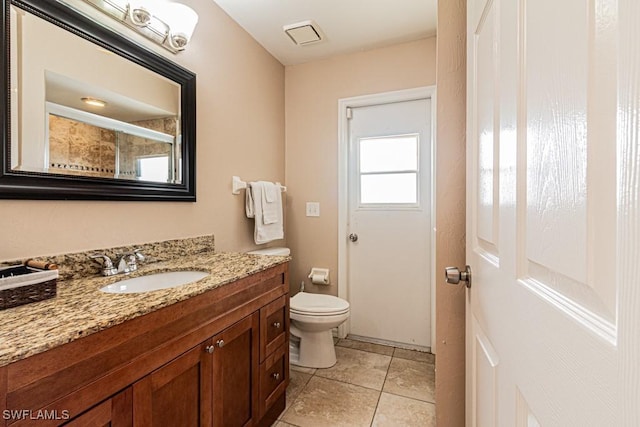 bathroom with toilet, vanity, walk in shower, and tile patterned flooring