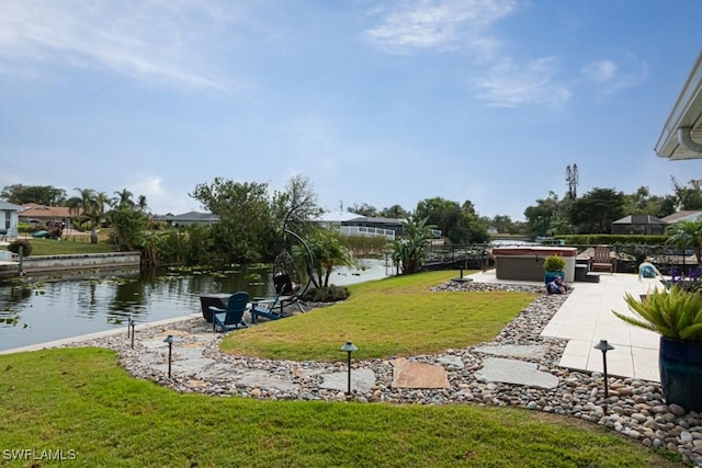 view of yard with a patio area, a hot tub, and a water view