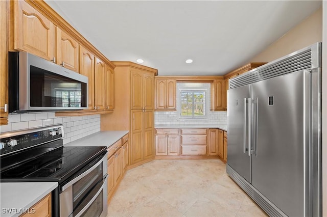 kitchen with stainless steel appliances, decorative backsplash, and light brown cabinets