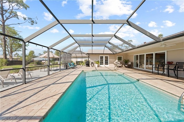 view of swimming pool with french doors, ceiling fan, glass enclosure, and a patio