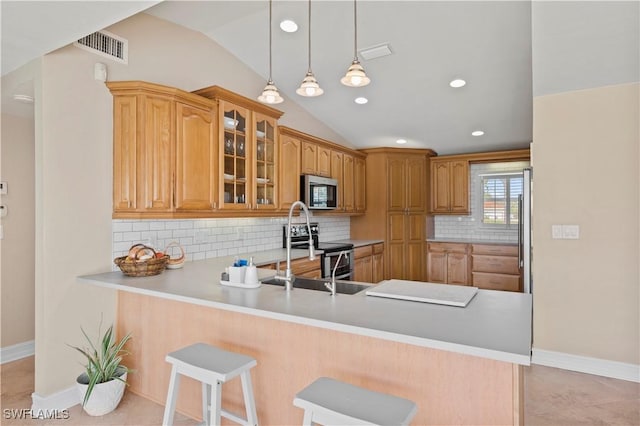 kitchen featuring lofted ceiling, kitchen peninsula, a breakfast bar, and tasteful backsplash