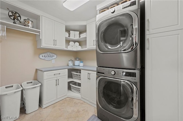 laundry room featuring stacked washing maching and dryer and cabinets