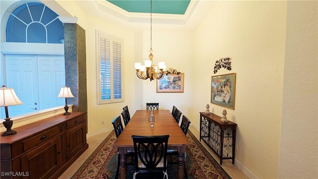 dining area with a notable chandelier, a raised ceiling, and crown molding