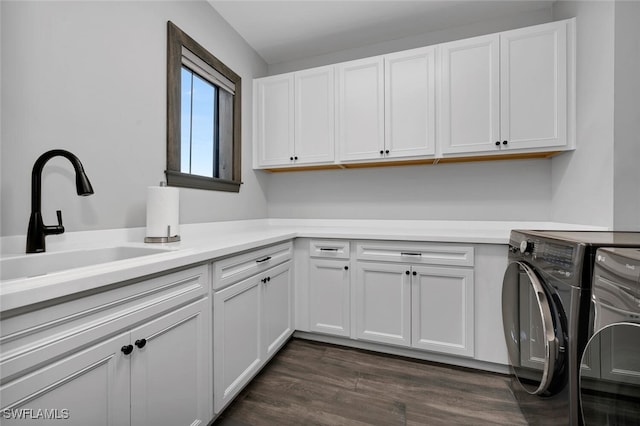 laundry room featuring sink, cabinets, washer and clothes dryer, and dark hardwood / wood-style floors