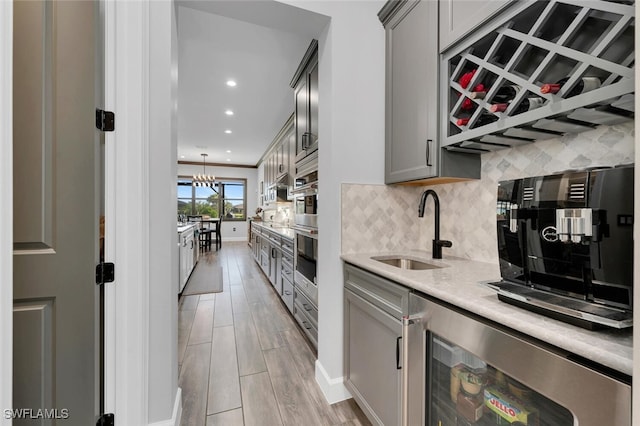 kitchen featuring sink, a chandelier, hanging light fixtures, and gray cabinets