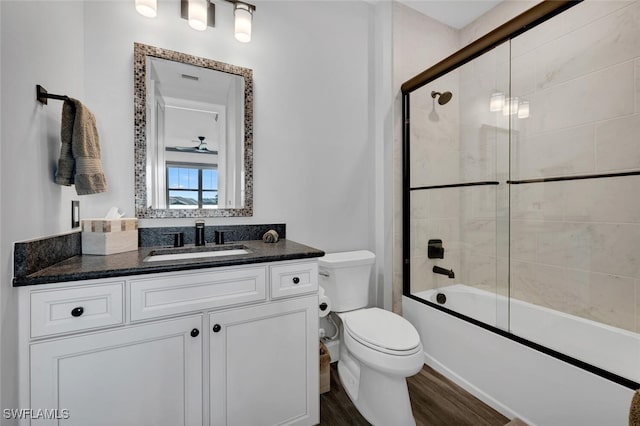 full bathroom with combined bath / shower with glass door, hardwood / wood-style floors, vanity, and toilet