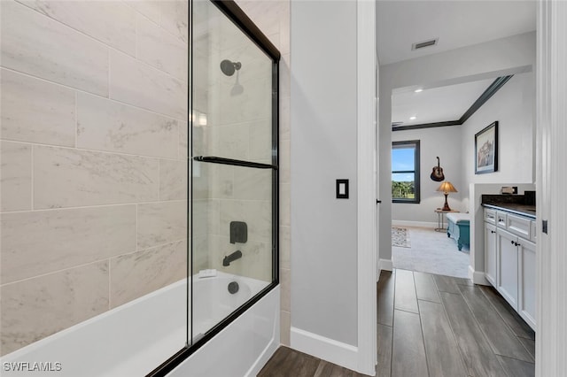 bathroom featuring shower / bath combination with glass door, ornamental molding, and vanity