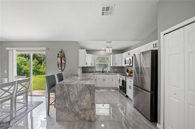 kitchen featuring light stone counters, stainless steel appliances, sink, pendant lighting, and white cabinetry