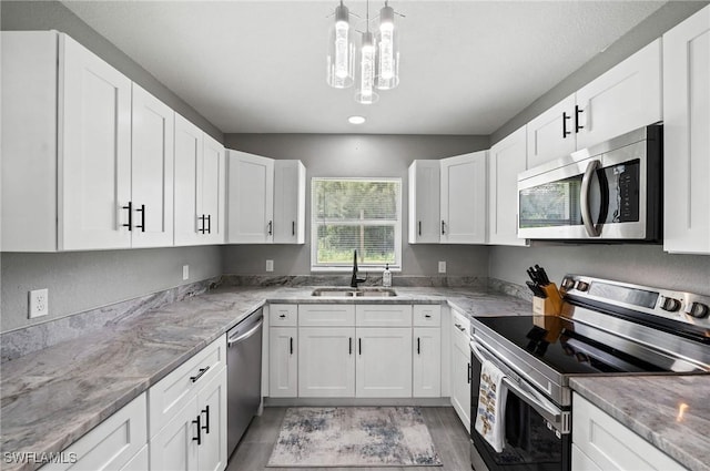 kitchen with white cabinetry, sink, light stone counters, a notable chandelier, and appliances with stainless steel finishes