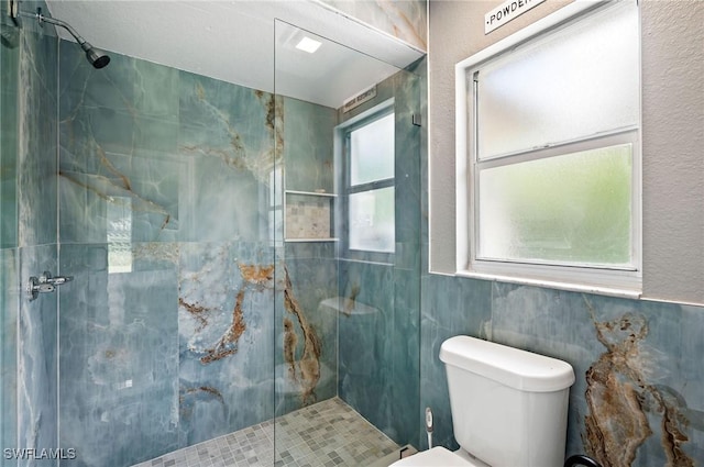 bathroom with tiled shower and toilet