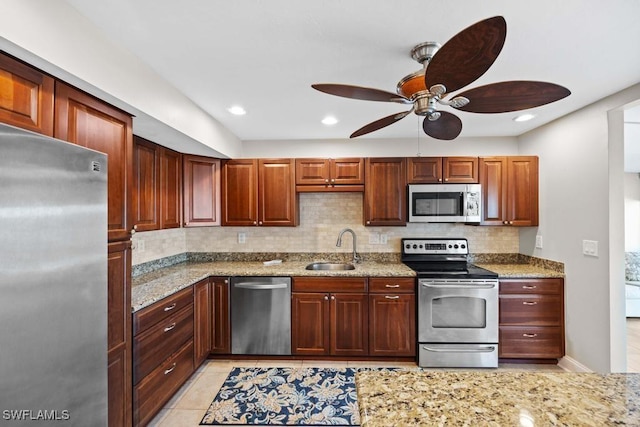 kitchen with light stone counters, light tile patterned floors, sink, and appliances with stainless steel finishes