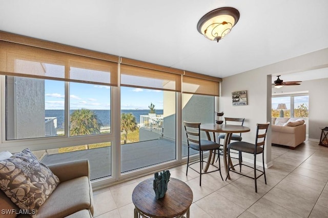 sunroom / solarium with ceiling fan and a water view